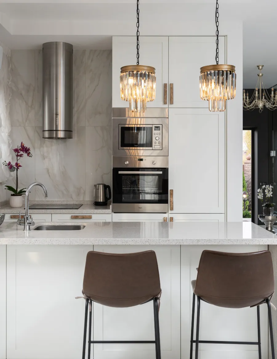 White Shaker wall and tall cabinets with brass pulls around a built-in oven
